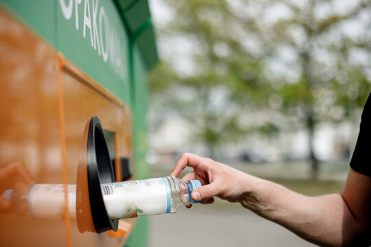 Man hand puts plastic bottle to the Recycling machine. Shoppers return their bottles and cans.kaucja