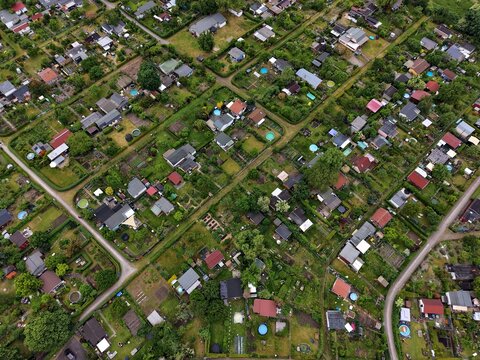 Aerial view of allotment gardens with small sheds, lush green vegetation, and narrow paths in Berlin, Berlin, Germany.