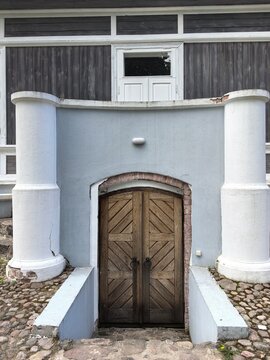 Traditional 19th-century estate architecture featuring brick archway and wooden basement doors. Local lore tourism and historic preservation guide.