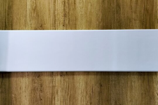 Blank white horizontal rectangular sign on a textured wooden background with copy space for text, design, or mockup.