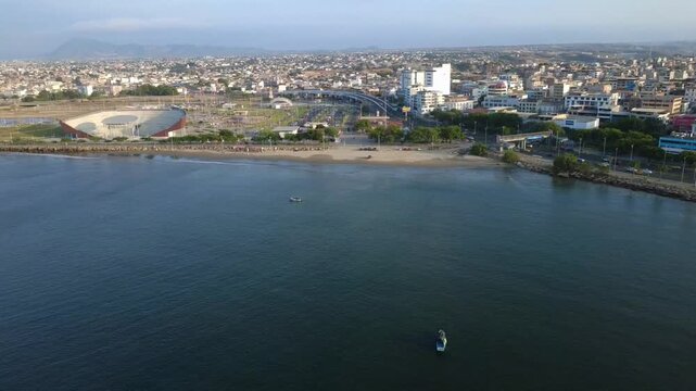 Aerial view of neighborhoods in the city of Manta, from the Pacific Ocean coast with fishing boats in the electric blue sea of ​​Ecuador in South America.