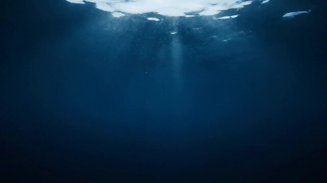 Underwater sunlight rays penetrate deep ocean water or Rays of sunlight penetrate underwater creating abstract blue patterns