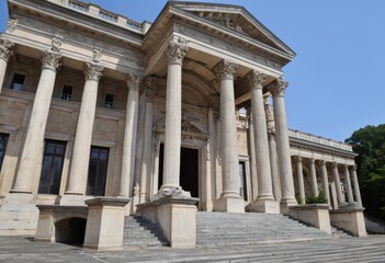 Fototapeta premium Historic European building exterior featuring massive stone columns and carved facade