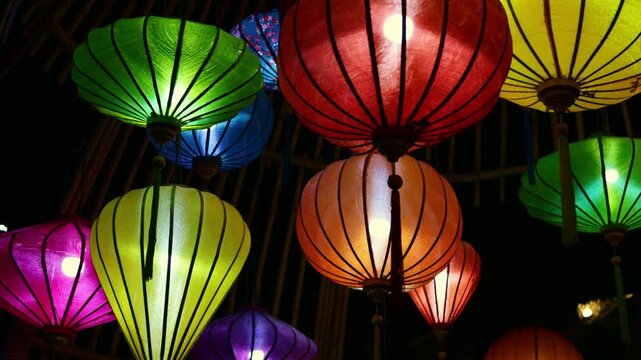 Multicolored silk lanterns gently swaying and glowing with warm light, creating a festive and traditional ambiance during a nocturnal celebration, a symbol of oriental culture and artistry