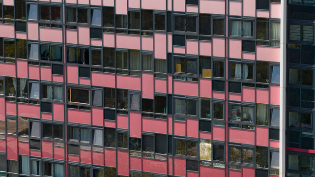Aerial view of a modern apartment building facade featuring pink panels and dark window frames in Zeist, Utrecht, Netherlands.