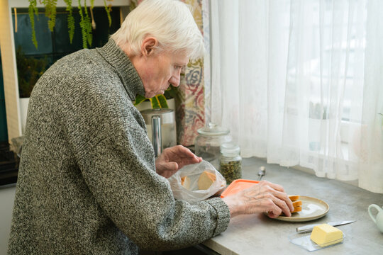 An older adult is in kitchen making his morning meal. The image captures start of new day and independence of senior living. Grandpa getting breakfast ready.