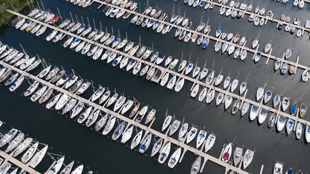 Aerial view of Marina Muiderzand with rows of sailboats and yachts docked at the piers in Almere, Flevoland, Netherlands.