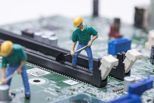 Miniature workers repairing circuit board and computer hardware