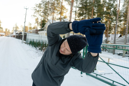 A forty-year-old runner does side bends with arms raised as a post-run stretch outdoors. He cools down in cold weather after his run.