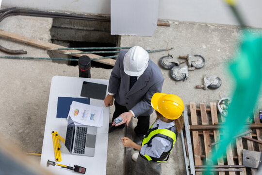 Top view of serious construction engineer and professional manager discussing architectural plan building project site looking focused working together wearing safety helmet hardhat holding