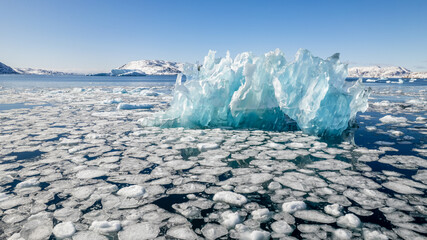 Dramatic blue glacier ice in a frozen arctic fjord with floating ice pieces and snowy mountain scenery in Narsaq, Kujalleq, Greenland © vadim.nefedov