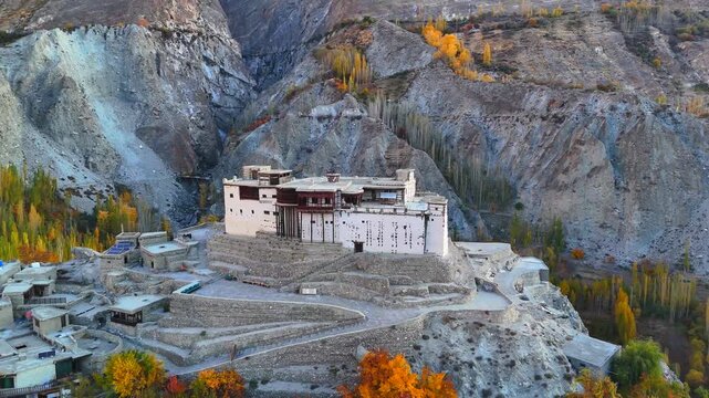 Aerial view of the historic Baltit Fort perched on a hill surrounded by rugged mountains and autumn foliage in Karimabad, Gilgit Baltistan, Pakistan.