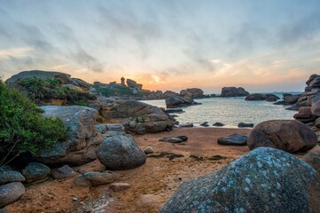 Sunset over the unique pink granite coast with giant boulders and the famous Mean Ruz lighthouse on the horizon, located in Ploumanac'h, Perros-Guirec, Brittany region, France, Europe. © Ivan