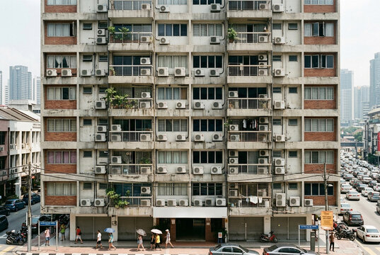 Many air conditioner units on facade of crowded urban apartment