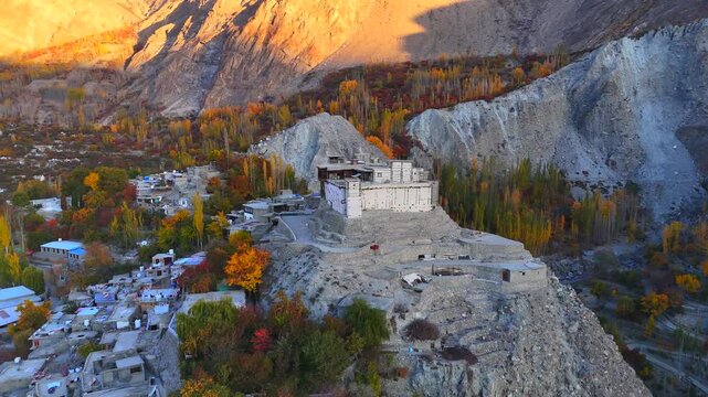 Aerial view of Baltit Fort surrounded by autumn trees and traditional houses in the Hunza Valley Karimabad, Gilgit Baltistan, Pakistan.