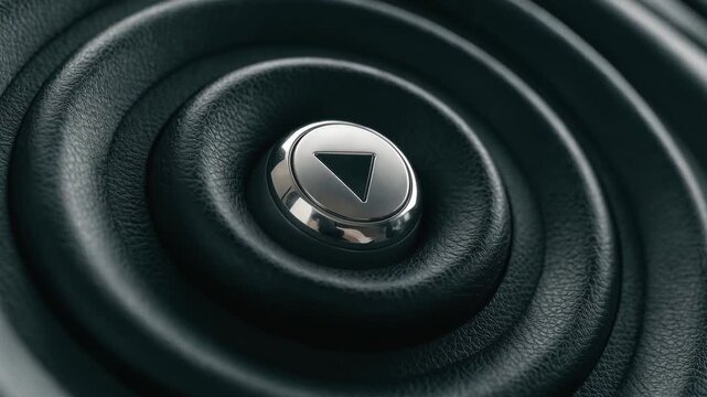 Sleek metallic play button centered within concentric rings of textured black leather.