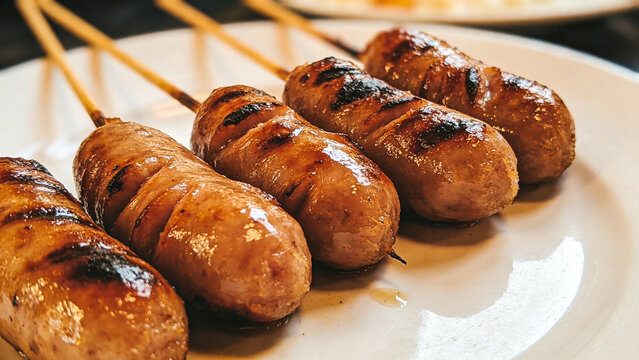 Thai grilled fermented sausage, sai krok isan, white ceramic plate.