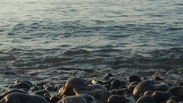 The slow, melancholic movement of a wave rolling over large and small pebbles on the shore of a sea or ocean
