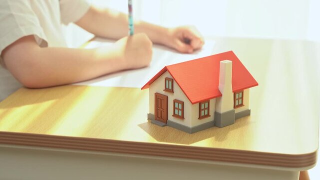 House and child drawing at the table. Affordable housing. supports ownership and stability. Real estate policies improve accessibility, reduce costs and encourage community development.