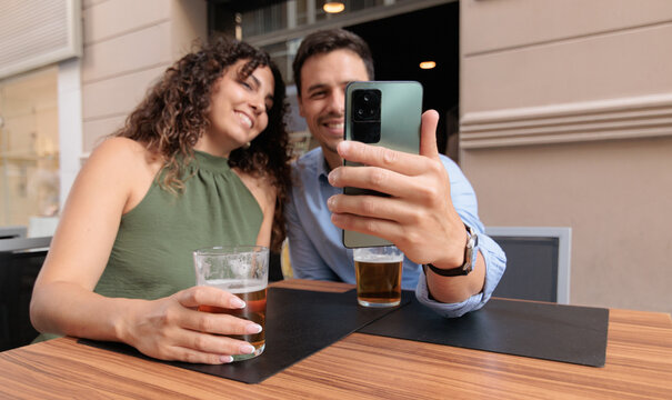 A man and a woman are on a video call while having a beer