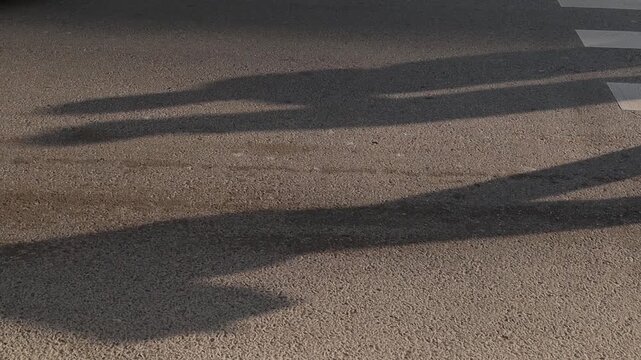 Evening city street with long human shadows and warm sunlight on asphalt