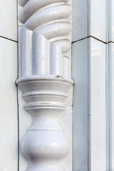 Obraz premium Close-up of a white glazed ceramic architectural column showing ornate moldings, rounded forms and subtle wear. The image emphasizes texture, reflection, crackle glaze, elegant vintage craftsmanship