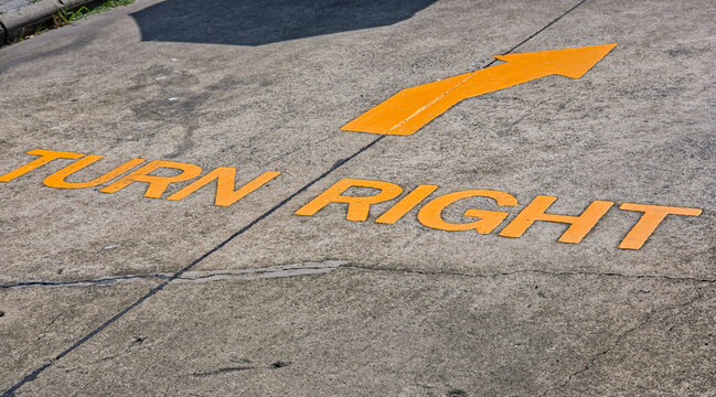 High Angle View of Yellow Painted Turn Right Traffic Sign and Arrow on Concrete Ground Road Surface