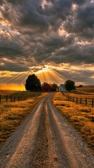 Dramatic sunset with sun rays breaking through storm clouds over rural farm with red barn and dirt road
