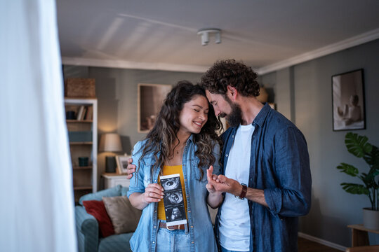 Happy couple announcing pregnancy holding sonogram image