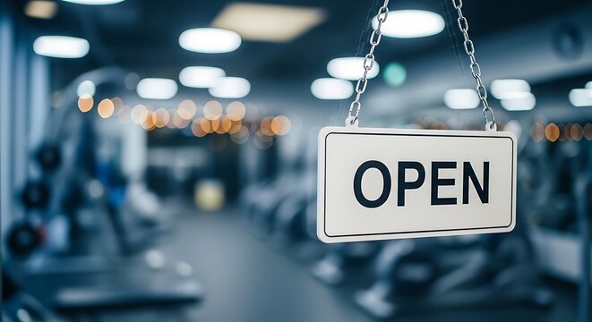 Hanging open sign in a blurred gym interior with fitness equipment