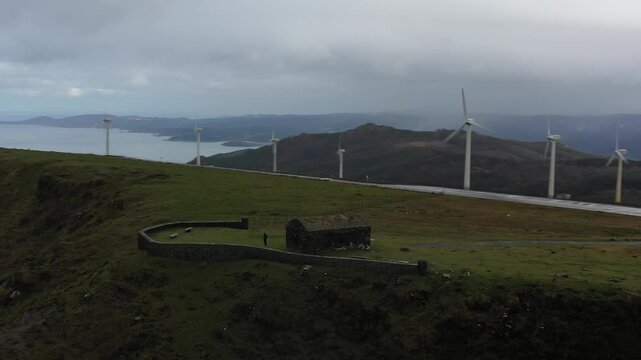Aerial view of Garita de Herbeira stone lookout on the high cliffs of Vixia Herbeira with wind turbines and the Atlantic Ocean in Meizoso, A Coruna, Spain.