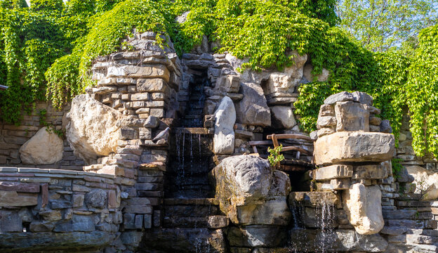 Rustic rock waterfall with cascading water and lush ivy in a landscaped garden