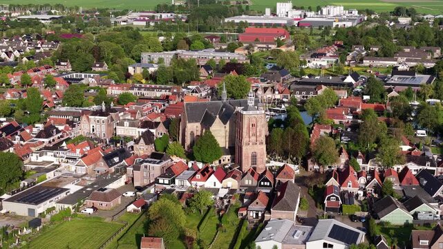 Aerial view of the historic Sint-Gertrudiskerk surrounded by traditional red-roofed houses and lush green trees in the town center of Workum, Friesland, Netherlands.
