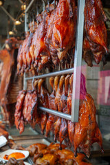 Obraz premium Mahogany coloured whole roast ducks hanging on racks in a front window of a restaurant in Chinatown. Toronto, Ontario, Canada. 