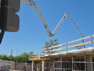 Concrete pump truck boom extended over a new floor slab under construction, viewed from next to the driver's cabin. © Mevhis