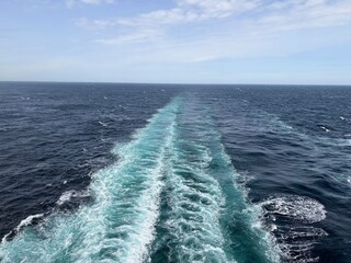 Boat wake creating striking patterns in vibrant blue-green ocean, aerial marine landscape with sparkling water surface, tropical travel, coastal adventure, navigation and tourism theme © Stacey