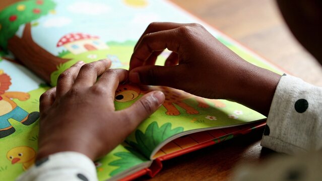 Child hands exploring colorful illustrated picture book promoting early literacy learning development education interactive reading activity preschool childhood curiosity cognitive growth language 
