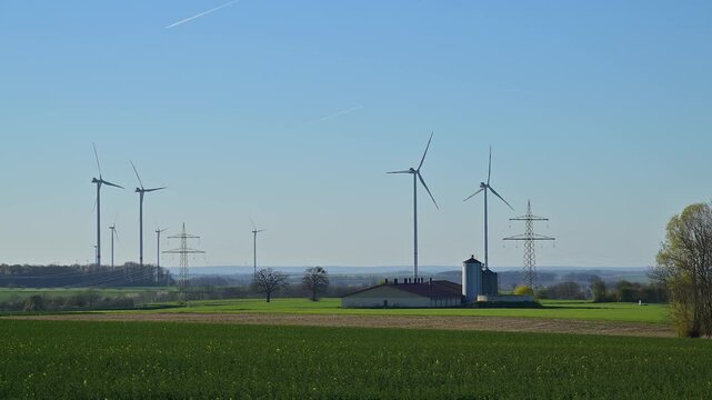 Windr&auml;der und Stromleitungen auf einer gr&uuml;nen Wiese mit einem Bauernhof, Custenlohr, Uffenheim, Landkreis Neustadt an der Aisch-Bad Windsheim, Mittelfranken, Bayern, Deutschland