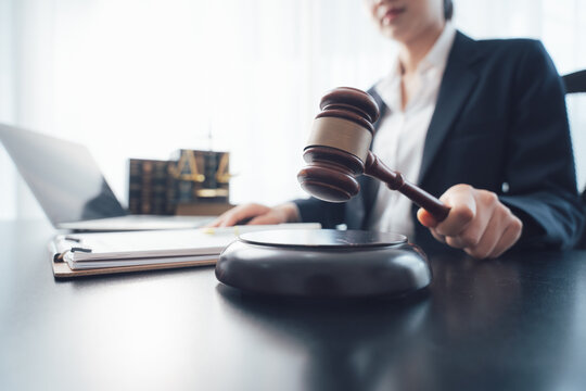 Lawyer in Action: A focused lawyer in a suit presides over legal proceedings, gavel in hand, seated at a desk with a laptop and law books, symbolizing justice and legal authority.