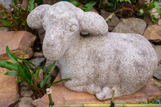 Adorable stone lamb garden figurine in a Japanese garden