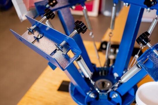Detailed shot of silkscreen printing press clamp mechanism and micro registration hardware inside a print shop