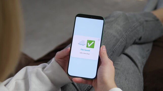 Safe in the cloud. Professional shot of a smartphone showing a File Saved confirmation with a green checkmark. Perfect for cybersecurity, data protection, and cloud storage marketing. High-quality