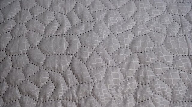Quilted grey fabric creating an abstract geometric pattern