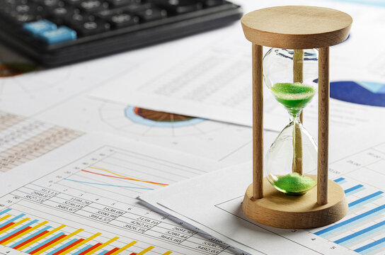hourglass on financial graphs and reports.Time schedule, working hours, business and finance.