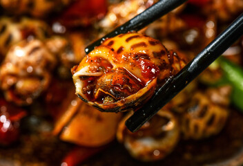 Spicy grilled snail with chopsticks in red chili sauce close up © DinhBaoTran
