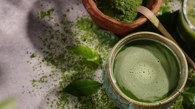 Hand whisking vibrant green matcha tea with traditional bamboo whisk, surrounded by matcha powder and tea-making ingredients. Illuminated by natural sunlight, creating an authentic tea ceremony scene