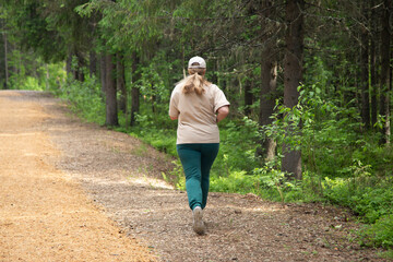 Obraz premium A fat woman runs through the park. Outdoor fitness.
