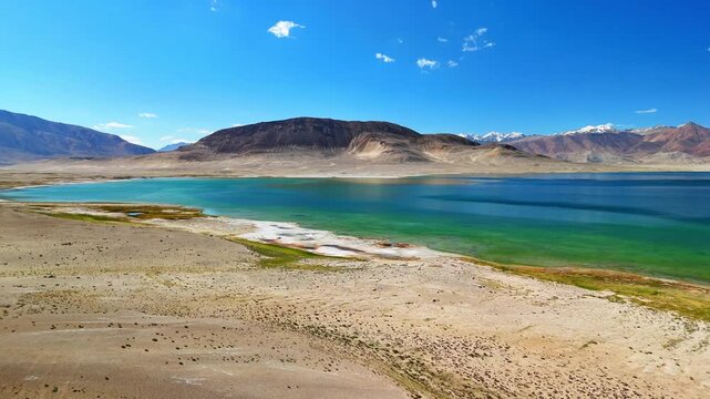 Aerial view of the turquoise waters and arid shoreline of Rabat Sasok-Kul lake under a clear blue sky in Rabat Sasok-Kul, Gorno-Badakhshan, Tajikistan.