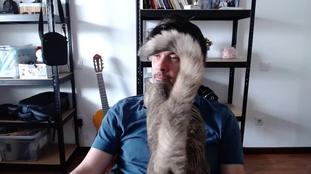 Man with cat in front of shelves with guitar and books