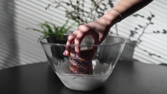 Close up of female hands dipping traditional easter bread into white icing creating festive holiday pastry decoration and showcasing homemade baking traditions